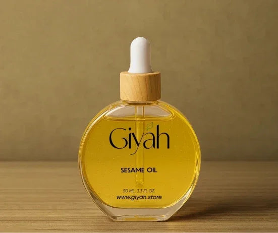 Round glass bottle of Giyah sesame oil with wooden dropper on wooden surface